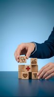 Businessman in dark suit stacking wooden blocks with healthcare icons including stethoscope, medical cross, heartbeat and caduceus symbol against blue background for health insurance and wellness concepts.
