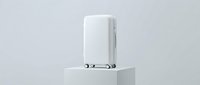 White hardshell carry-on suitcase with spinner wheels displayed on a white podium against a light gray background, minimalist travel luggage concept.