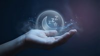 Hand holding glowing sleep bubble with Z letters floating above palm against dark starry background for wellness and rest concepts.