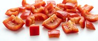 Fresh red bell pepper pieces chopped and diced on white background, isolated vegetable ingredients ready for cooking and meal preparation.