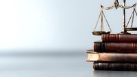 Vintage brass scales of justice on stack of old leather law books against neutral background, symbolizing legal system and jurisprudence principles.