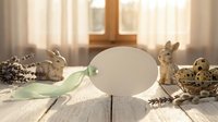 Easter egg decoration with bunny figurines and natural elements on rustic wooden table in warm sunlight for spring holiday celebration.