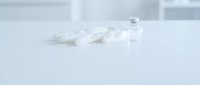 Medical syringe and glass vial with clear liquid on clean white surface for healthcare and pharmaceutical applications.