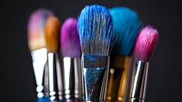 Colorful makeup brushes with vibrant blue and pink bristles against dark background, professional cosmetic tools for beauty artists and makeup application.