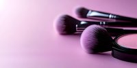 Professional makeup brushes and compact powder against pink background with soft focus and copy space for beauty and cosmetics industry.