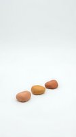 Three smooth oval stones in warm earth tones arranged on clean white background for spa wellness meditation and natural therapy concepts.