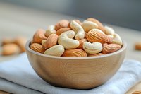 Mixed nuts almonds cashews in wooden bowl on white cloth healthy snacking protein rich food ingredients for cooking and baking nutritious diet.