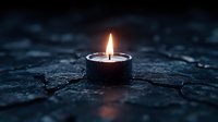 Single burning candle flame glowing in dark moody atmosphere on textured stone surface, creating peaceful ambiance and warm light reflection.