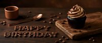 Chocolate cupcake with swirled frosting on wooden board, happy birthday text made of coffee beans on dark rustic table, celebration concept.
