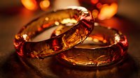 Amber resin bracelets with warm golden-red tones arranged on dark surface with bokeh lighting, suitable for jewelry, fashion, and luxury product design.