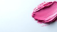 Pink lipstick smear on white background with creamy texture and scattered particles for cosmetic and beauty product design applications.