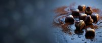 Chocolate truffles dusted with cocoa powder arranged on dark slate surface with copy space for bakery, confectionery, dessert, and gourmet food projects.