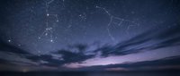 Night sky with constellation patterns and stars over dramatic cloudy horizon at twilight for astronomy and celestial navigation educational content.