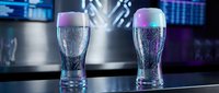Two empty beer glasses with colorful gradient lighting effects on modern bar counter in nightclub or restaurant setting for beverage service concepts.