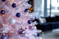 White Christmas tree decorated with purple and silver ornaments and warm lights in modern home interior for holiday celebration.