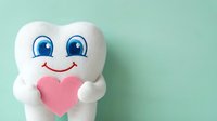Cute white tooth mascot character holding pink heart on mint green background for dental care and oral health campaigns.