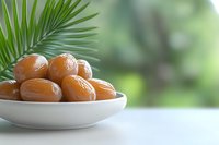 Fresh sweet dates in white ceramic bowl on light table with palm leaf and soft green bokeh background, healthy natural dried fruit snack.