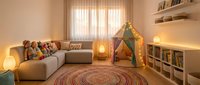 Cozy modern playroom interior with colorful teepee tent, sectional sofa, round braided rug, and organized toy storage shelves creating warm family space.