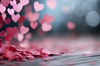 Romantic pink and red hearts scattered on surface with dreamy bokeh lights background for Valentine's Day celebrations and love themed designs.