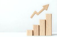 Wooden blocks arranged as ascending bar graph with upward trending arrow, representing business growth and success on white background.