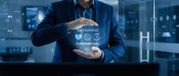 Professional businessman in suit presenting customer care support concept with protective hands gesture in modern office environment with digital interface.
