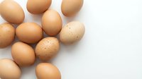 Fresh brown eggs scattered on white background for cooking and baking recipes. Natural organic farm produce for healthy breakfast and culinary preparations.