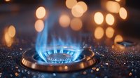 Blue gas stove flame burning with golden bokeh lights in dark kitchen background, water drops create sparkle effect on black surface.