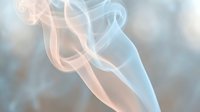 Elegant flowing smoke with soft blue and orange hues creating abstract patterns against blurred background for creative design projects.