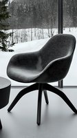 Modern gray armchair by panoramic window overlooking snowy winter forest landscape. Minimalist interior design with contemporary furniture piece.