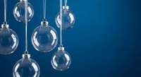 Clear glass Christmas ornament balls hanging against deep blue background with copy space for holiday decorations and seasonal design projects.