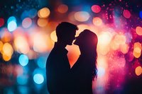 Romantic silhouette of couple about to kiss against vibrant bokeh lights background with blue and orange glowing circles creating dreamy atmosphere.