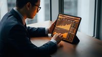 Professional businessman analyzing financial data charts and graphs on laptop computer screen in modern office environment for business analytics and reporting.