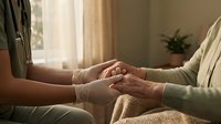 Caring hands of young woman holding elderly person's hands in warm sunlit room showing compassion, support and intergenerational connection.