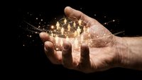 Male hand holding glowing light particles and sparks against dark background. Represents innovation, technology, energy, success, and digital transformation for business concepts.