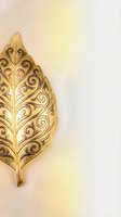 Ornate golden leaf with intricate swirl patterns on warm gradient background for luxury design projects and elegant decorative applications.
