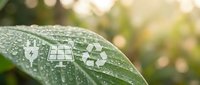 Green leaf with water droplets featuring white eco-friendly symbols including lightbulb, solar panel and recycling icon representing sustainability.