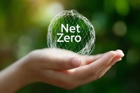 Female hand holding glowing net zero text in wireframe sphere against green bokeh background, representing environmental sustainability and carbon neutrality.