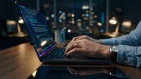 Software developer coding on laptop with programming interface in modern office workspace at night.
