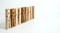 Row of wooden clothespins standing upright on white surface, natural wood texture, minimalist laundry concept with copy space for text.