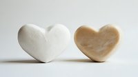 Two heart-shaped soap bars in white and beige colors on clean background for spa, wellness and skincare product photography.