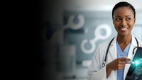 African American female doctor smiling confidently in medical facility with stethoscope and tablet displaying digital health technology interface.