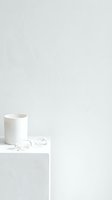 White ceramic mug with earbuds on minimalist shelf against textured wall. Isolated product mockup for branding, packaging design, and commercial use.