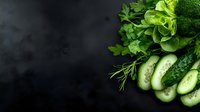 Fresh green vegetables and herbs arranged on dark slate background with copy space for healthy cooking and nutrition concepts.