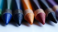 Macro view of colorful pencil tips in row showing texture and detail of graphite points against blurred background, artistic supplies for drawing and sketching.