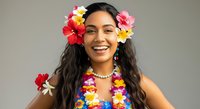Young woman with long dark hair and South Asian ethnicity wearing vibrant floral lei and colorful flower crown, smiling at camera against neutral background for tropical, summer, and celebration themes.