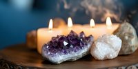 Burning candles with amethyst and clear quartz crystals on wooden surface creating peaceful meditation and spiritual healing atmosphere for wellness rituals.