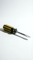 Yellow and black handled screwdriver with flathead tip isolated on white background casting shadow for tool and hardware projects.
