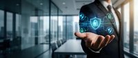 Professional businessman presenting cybersecurity shield icons and digital protection symbols floating above open palm in modern office environment.