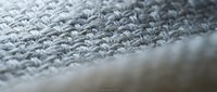 Gray knitted fabric texture with detailed stitch pattern showing soft wool yarn construction for cozy winter clothing and textile design projects.