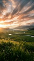 Dramatic sunrise over rolling green hills with winding river and golden sky, suitable for travel, nature, and landscape design projects.